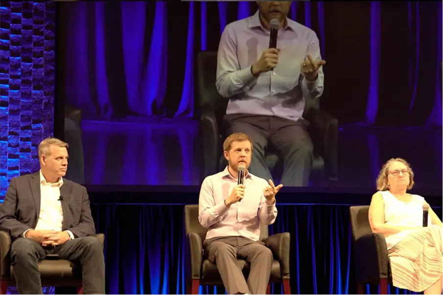 Panel discussion on a stage with three seated speakers.